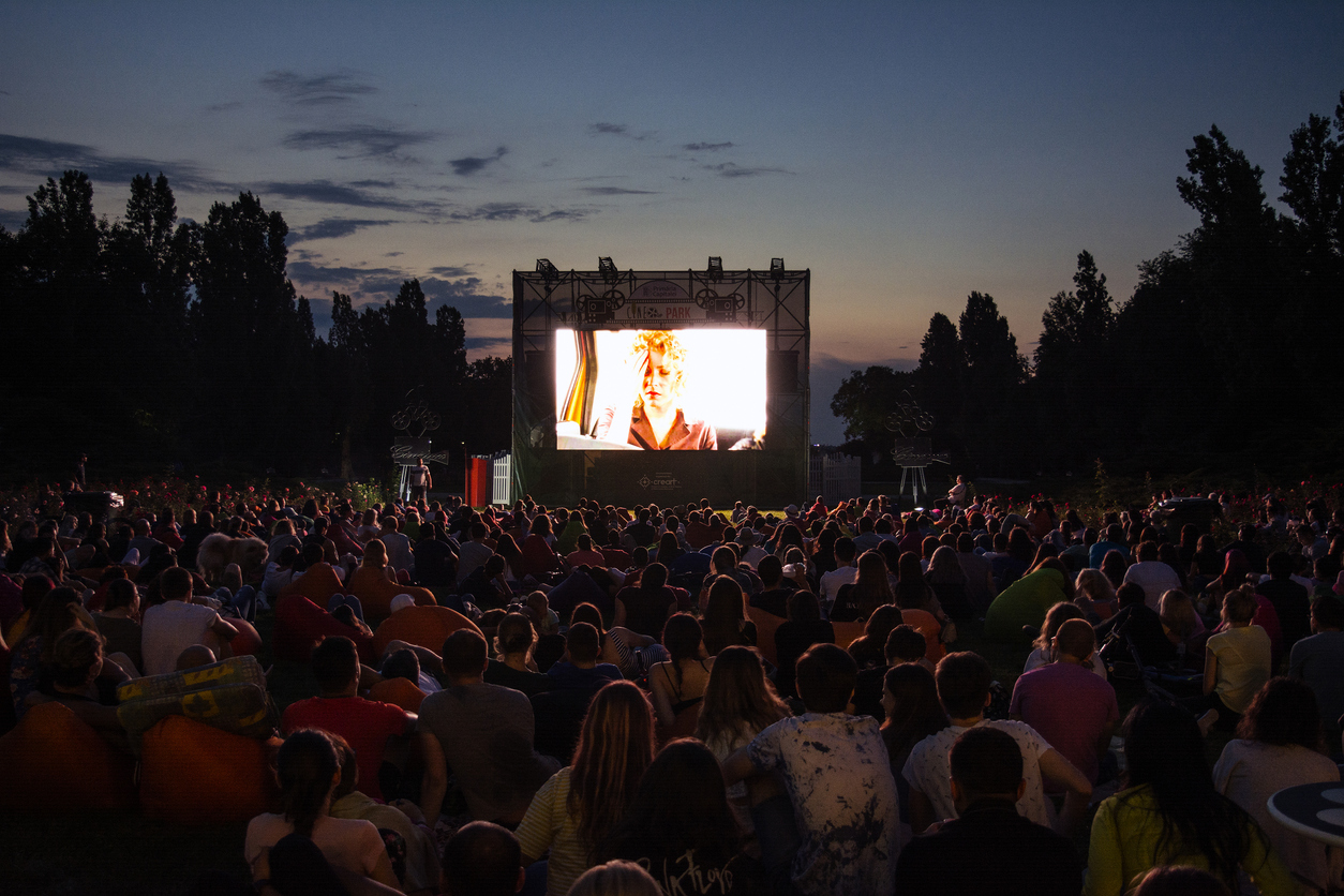 an outdoor, open-air cinema with a crowd of people watching