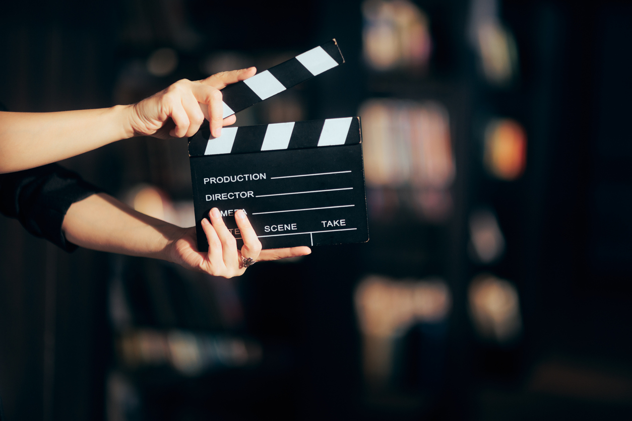 Hands holding a film slate directing a movie scene