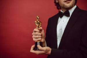 a man in suit holding a golden Oscar trophy